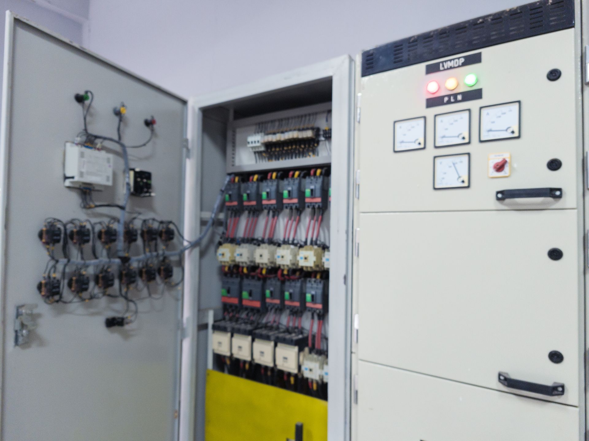 Open electrical control panel with meters, switches, wiring, and indicator lights
