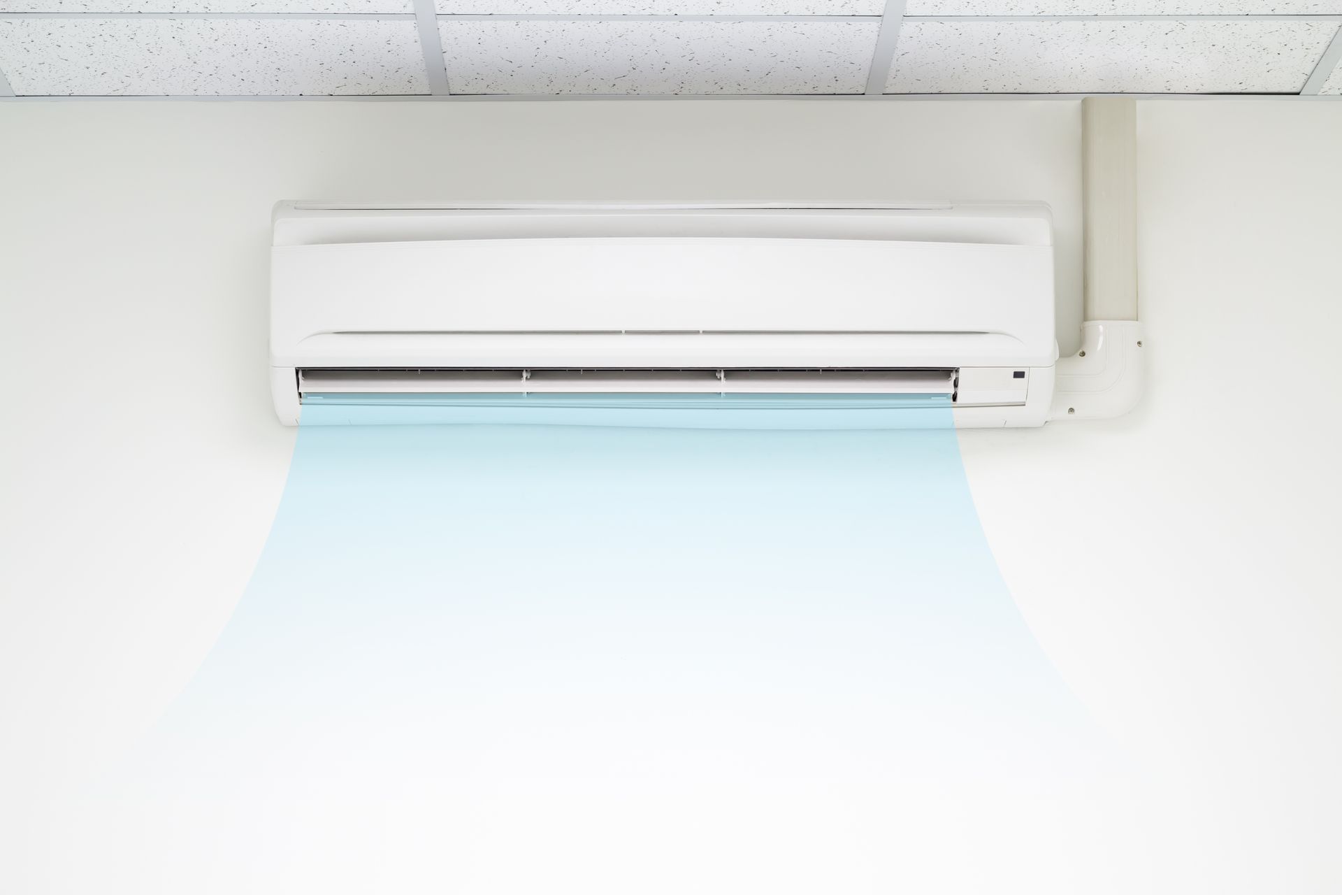 White wall-mounted air conditioner blowing cool air. Blue air stream visible, white wall, white ceiling.