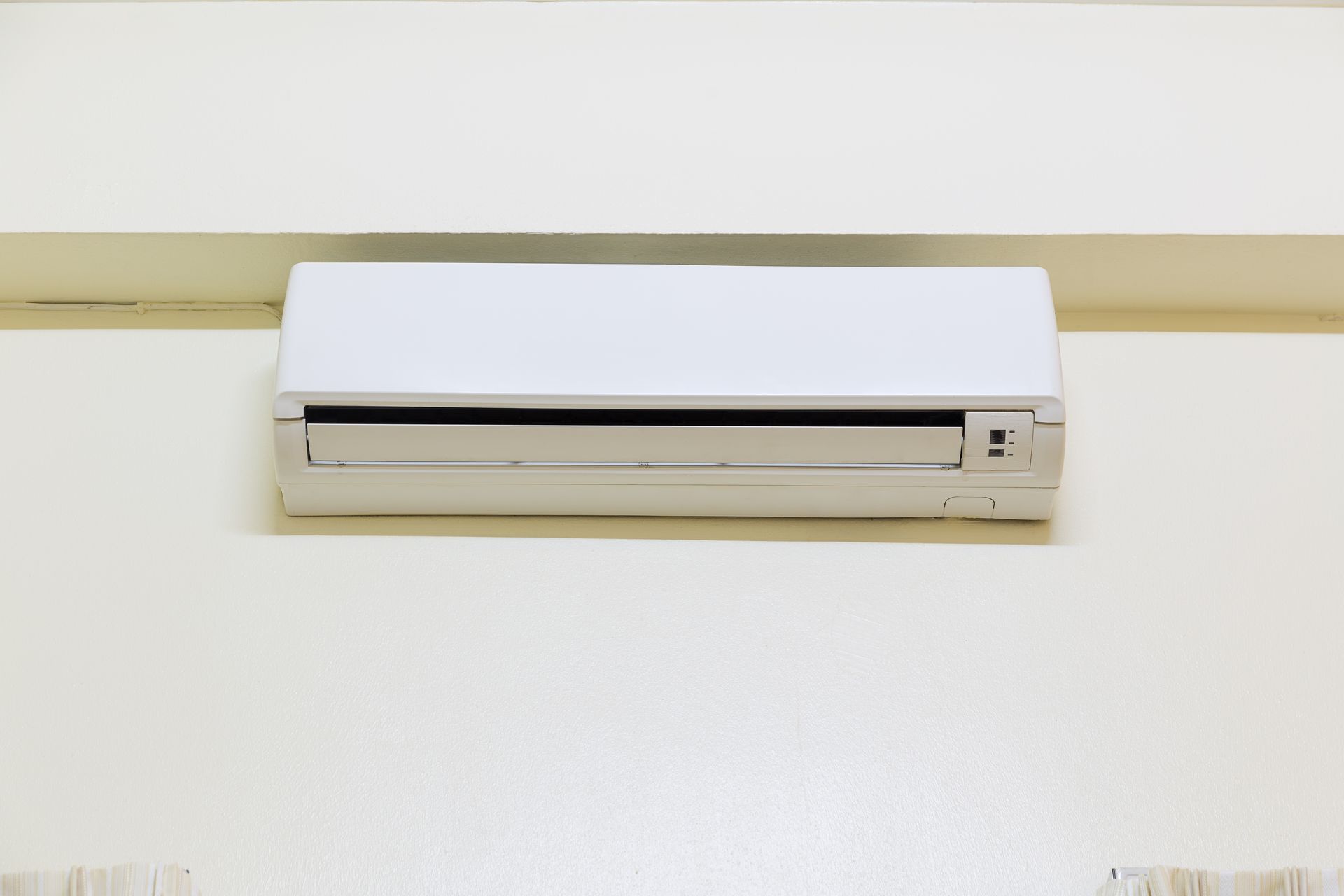 White air conditioning unit mounted on a white wall.