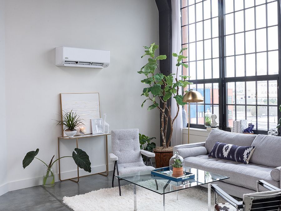 A living room with a couch , chair , coffee table and air conditioner.