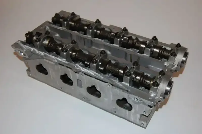 Two cylinder heads are sitting on top of each other on a white surface.