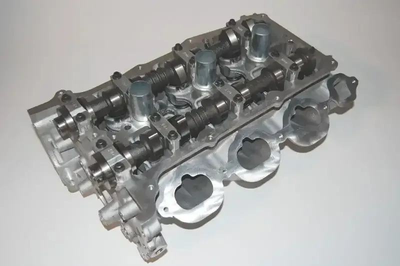 A close up of a cylinder head on a white surface