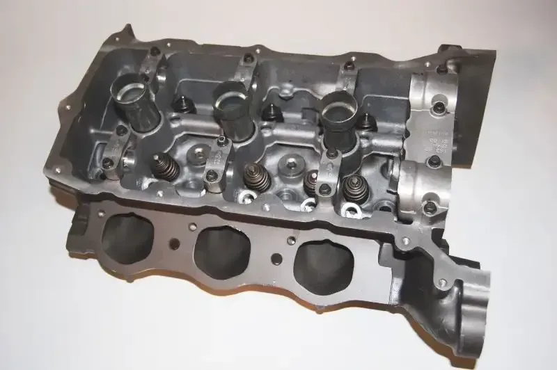 A close up of a cylinder head on a white surface