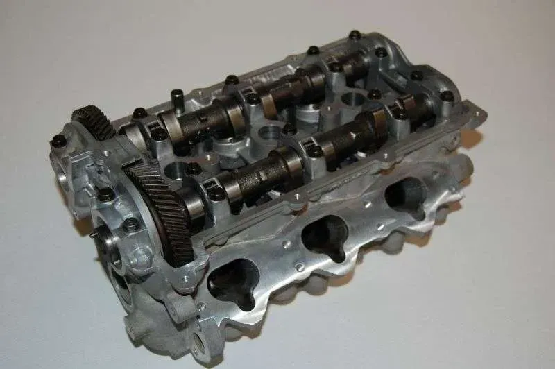 A close up of a cylinder head on a white surface.