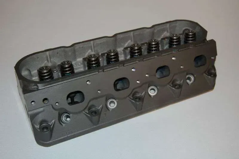 A close up of a cylinder head on a white surface.