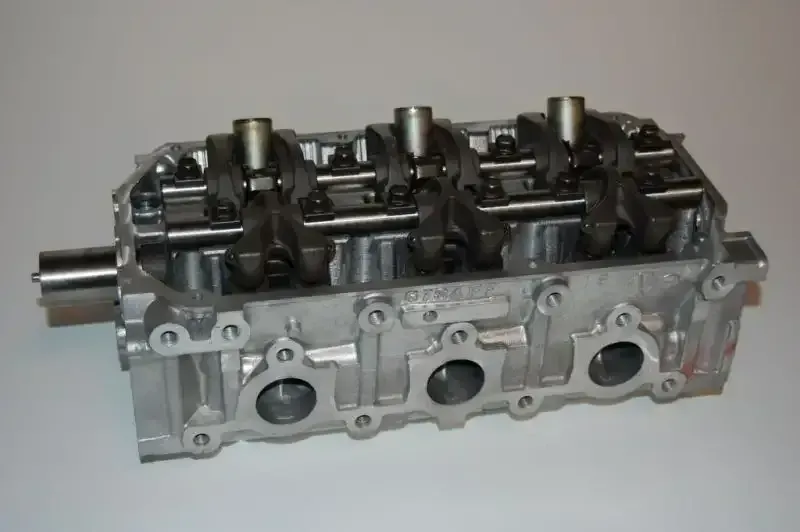 A close up of a cylinder head on a white surface.