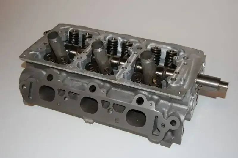 A close up of a cylinder head on a white surface.