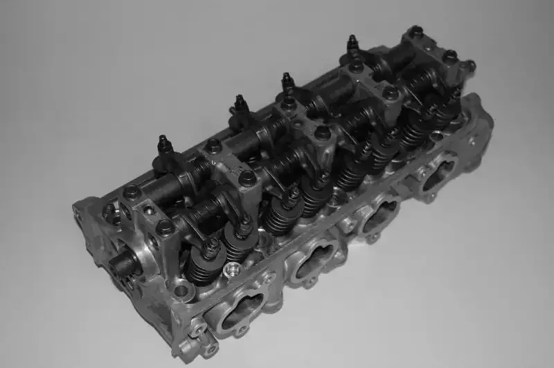 A close up of a cylinder head on a white surface.