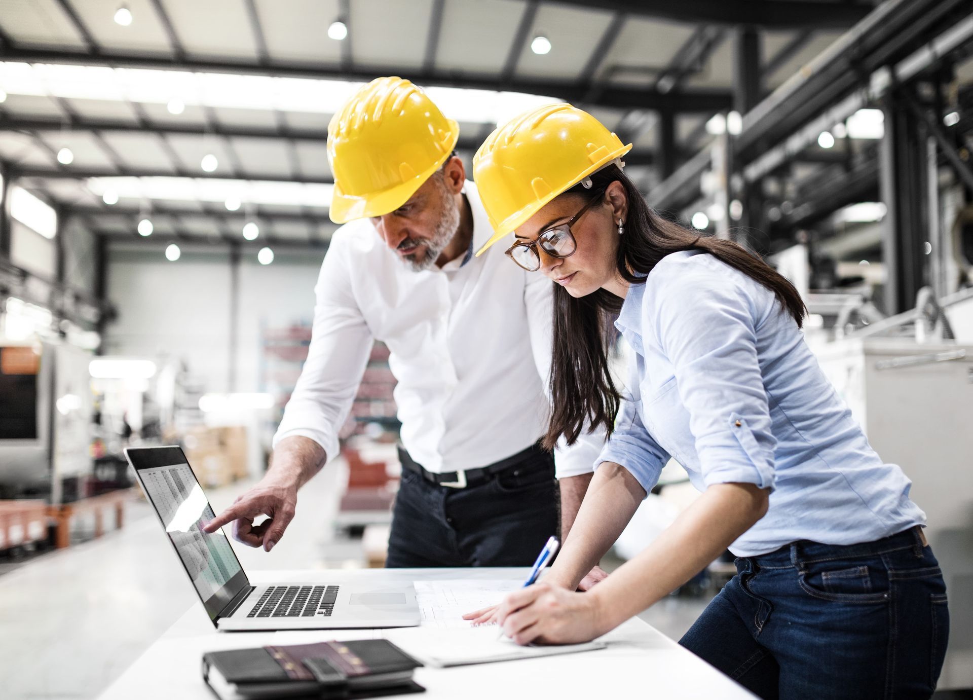 Two industrial project managers discussing electrical supply chain solutions inside a  facility 