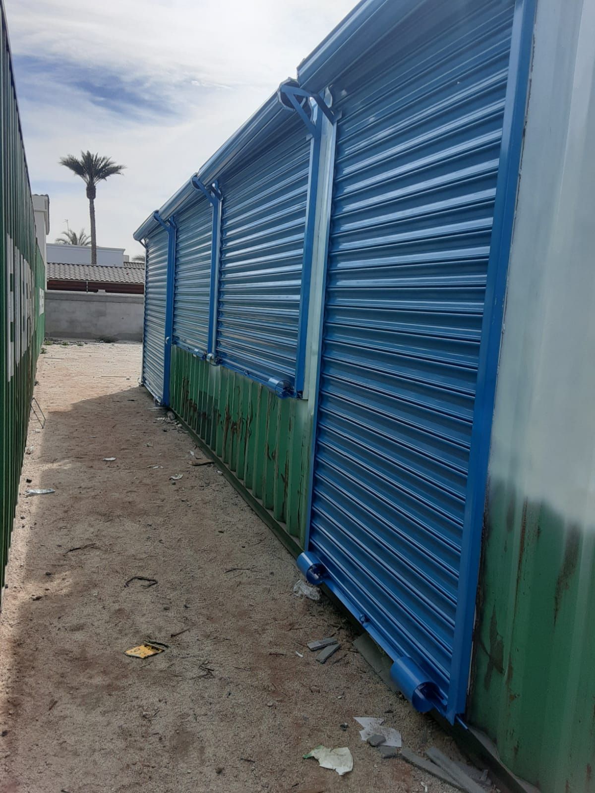 Una hilera de contraventanas azules en un edificio verde