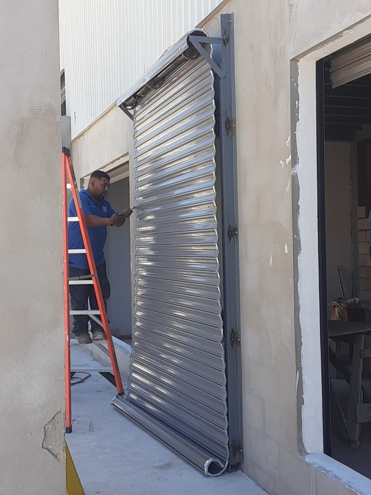 Un hombre está parado en una escalera junto a la puerta de un garaje.