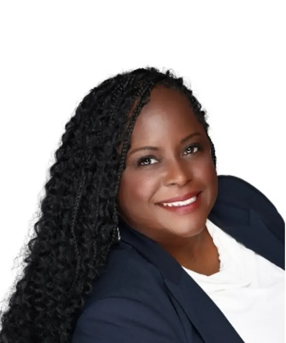 Smiling woman in a navy blazer and white top against a white background