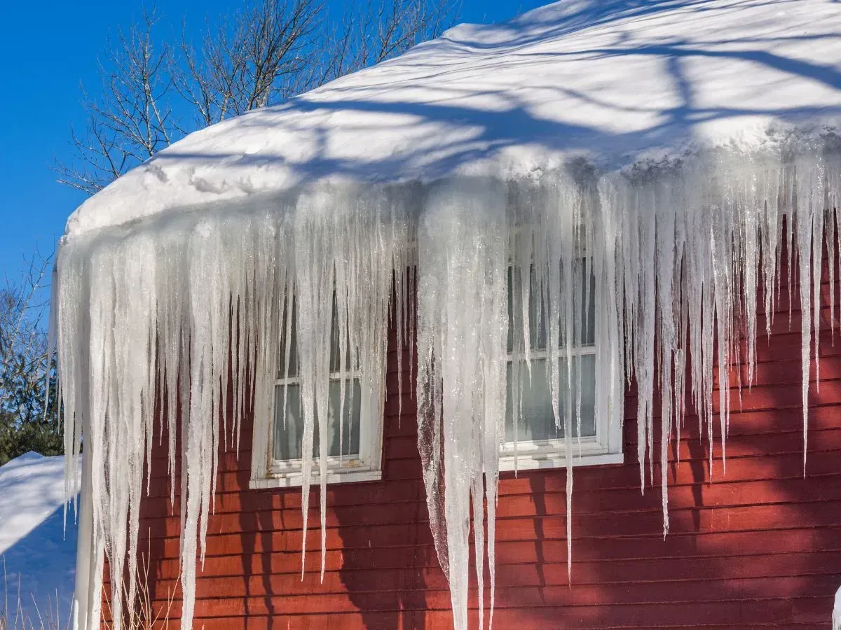 Large icicles hanging from a snow-covered house roof