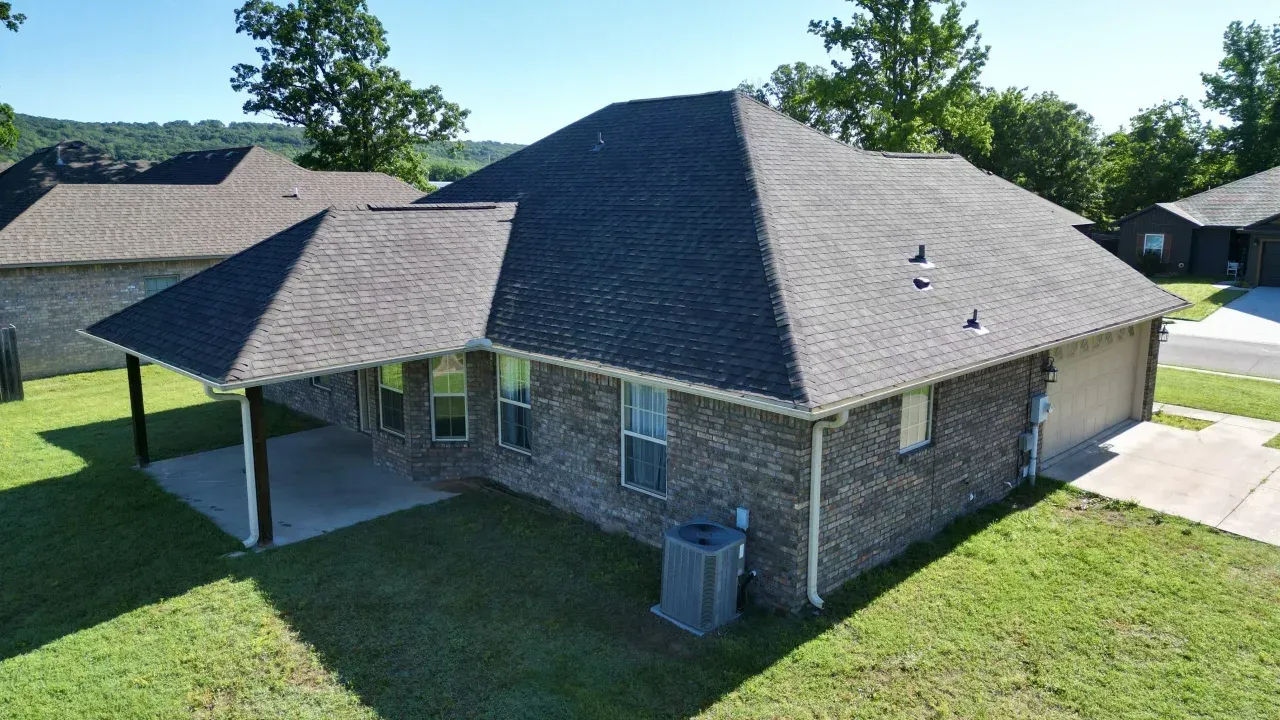Architectural shingle installation on a brown brick residential home with a covered patio in Maryland.