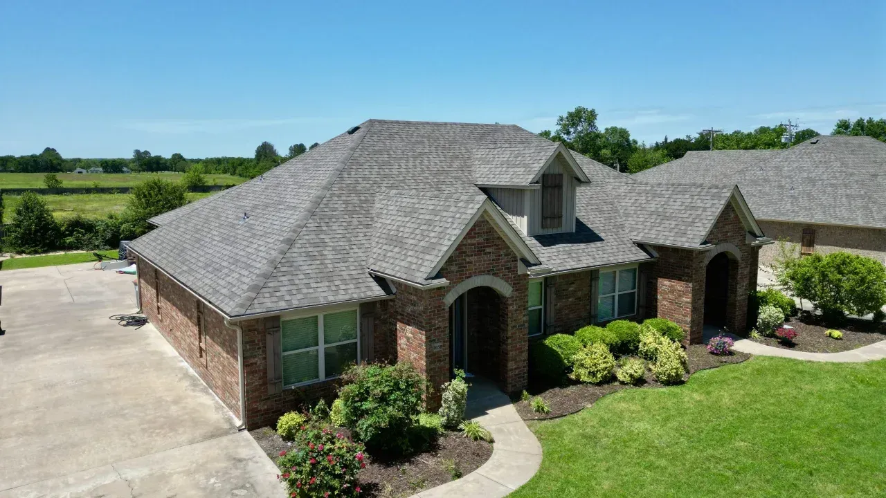 Single-story brick house with gray shingle roof and landscaped yard