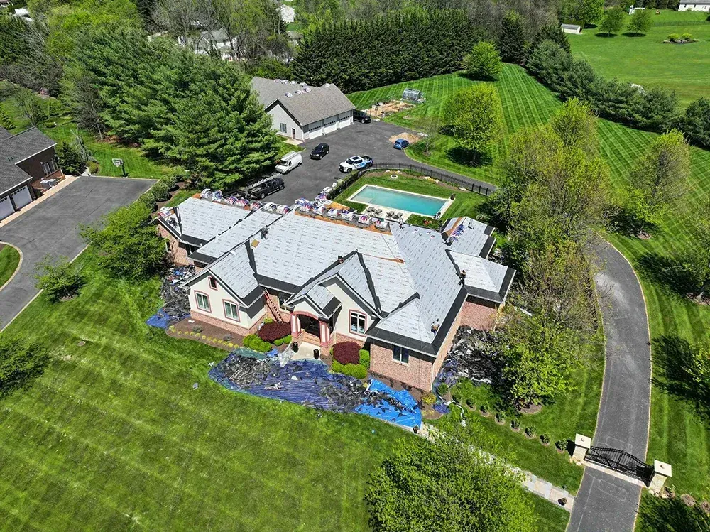 Asphalt shingle roof installation on a brick residential estate with a pool in Maryland.