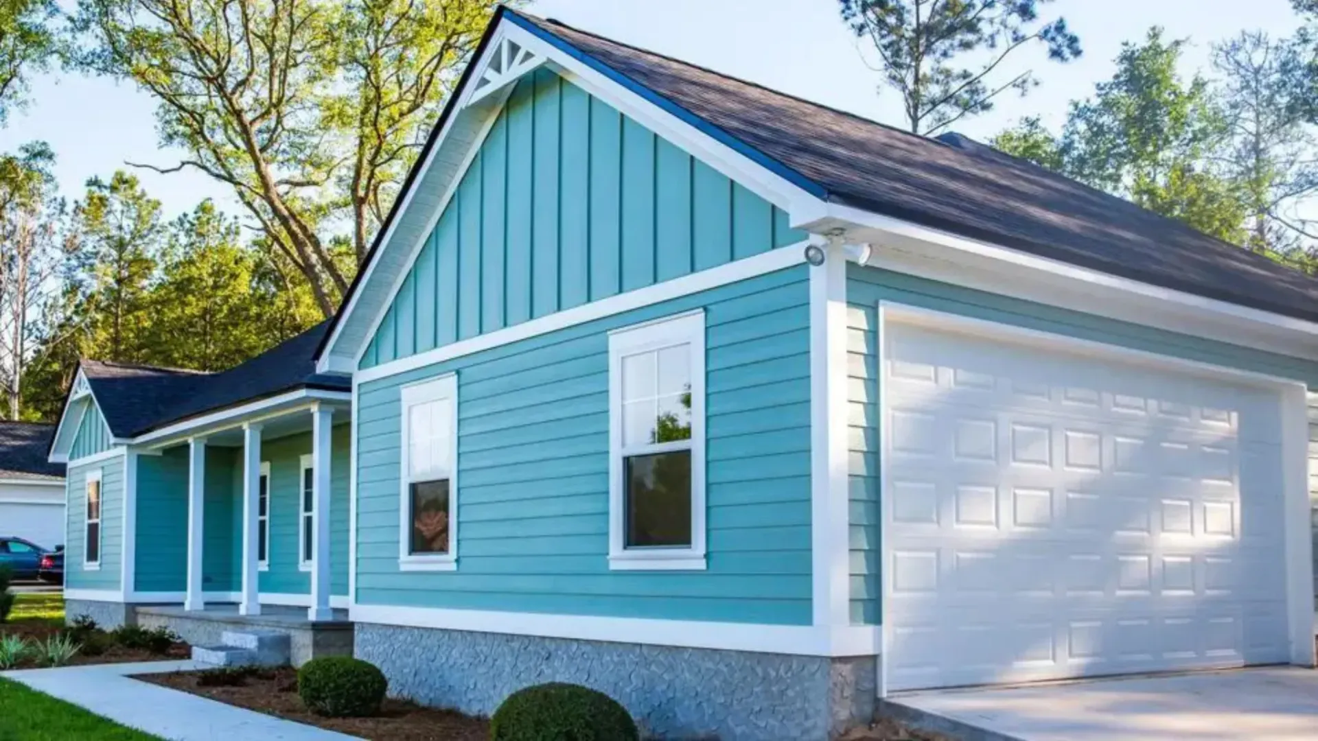 Blue house with white trim, garage door, porch, and dark roof.