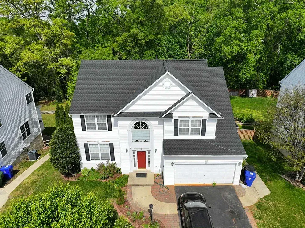 Asphalt shingle roof installation on a multi-story white residential home in Maryland.