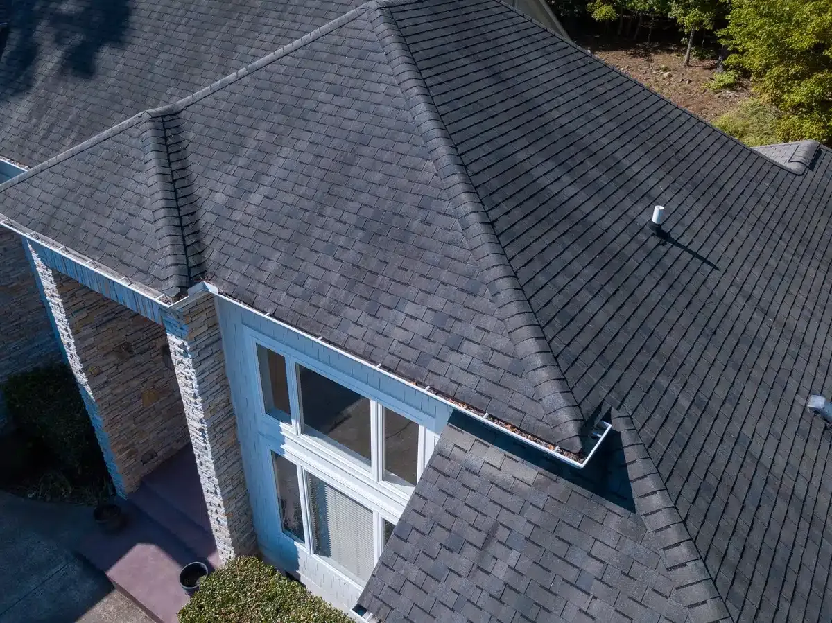 Overhead view of a house with a dark gray shingle roof, white trim, and a brick porch.