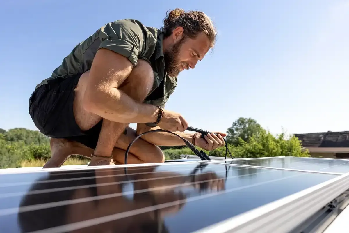 Man installing solar panels on a roof, sunny day.
