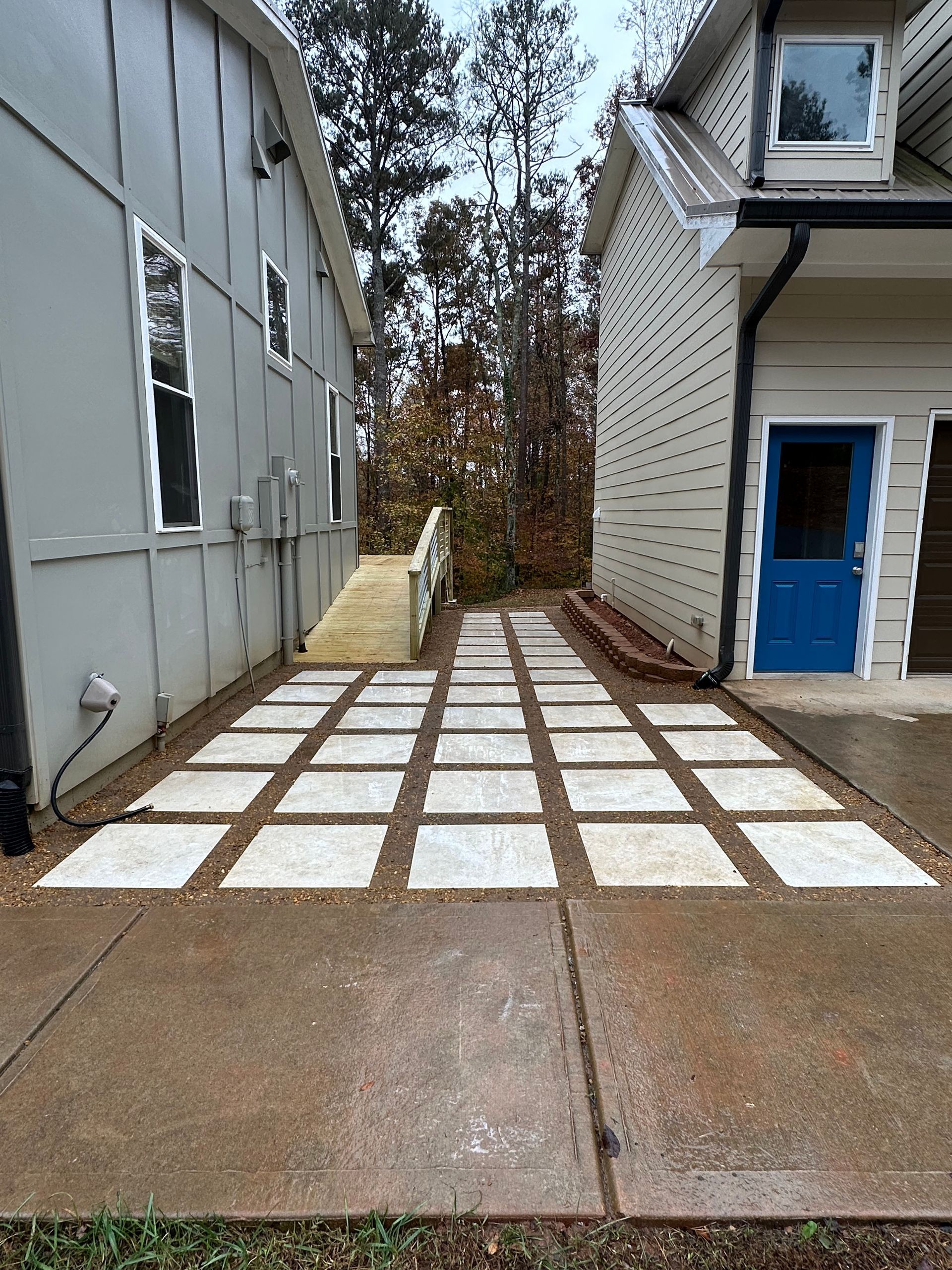 A concrete driveway leading to a house with a blue door
