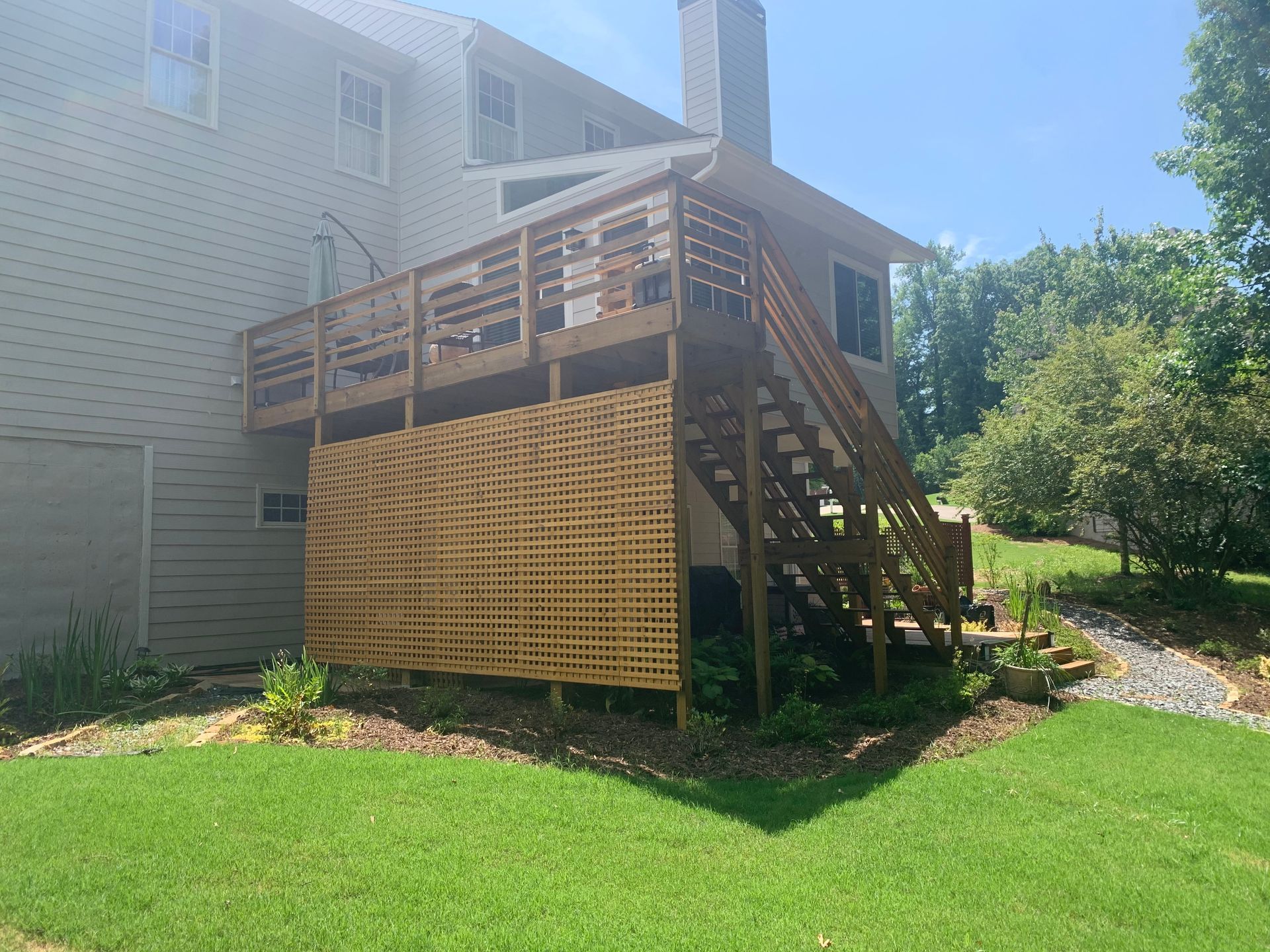 A house with a wooden deck and stairs in the backyard.