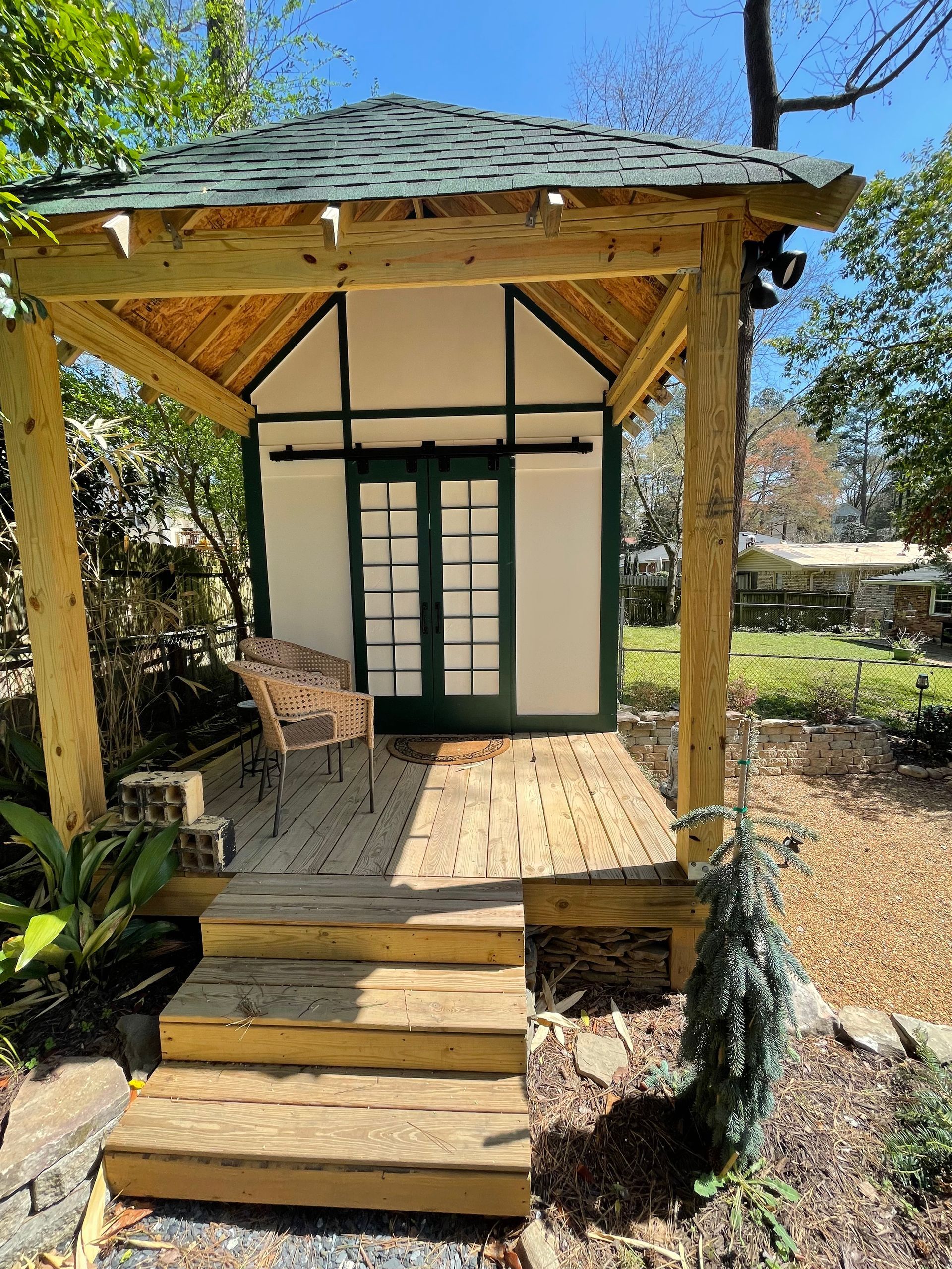 A wooden gazebo with a green roof and stairs