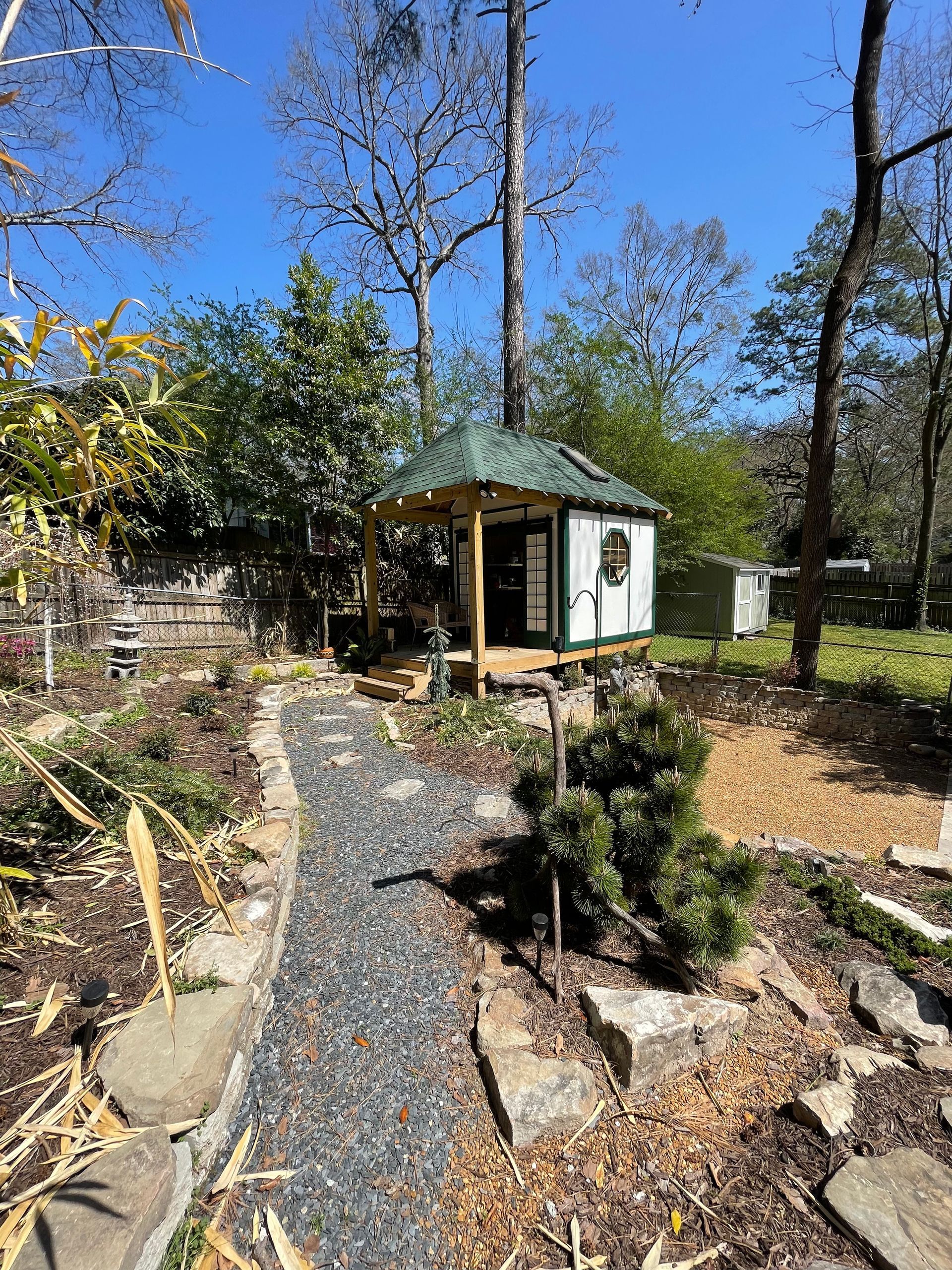 A small house with a green roof is surrounded by trees and rocks.