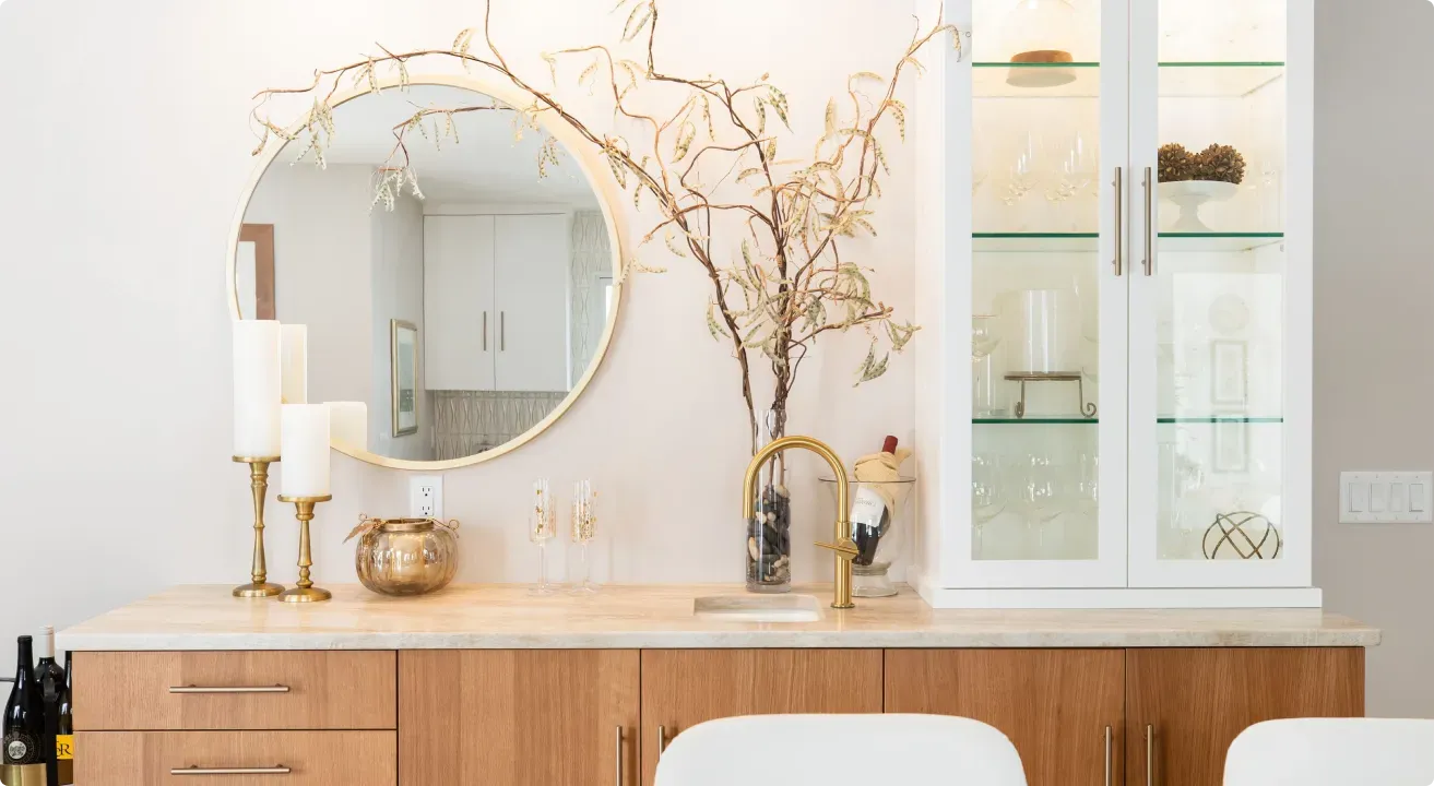 Bright console table with round mirror, white cabinet, and gold decor in a light airy room