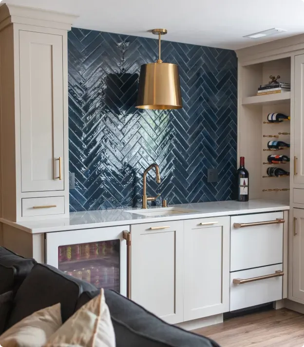 Modern kitchen bar with navy herringbone tile backsplash, brass pendant, and white cabinets