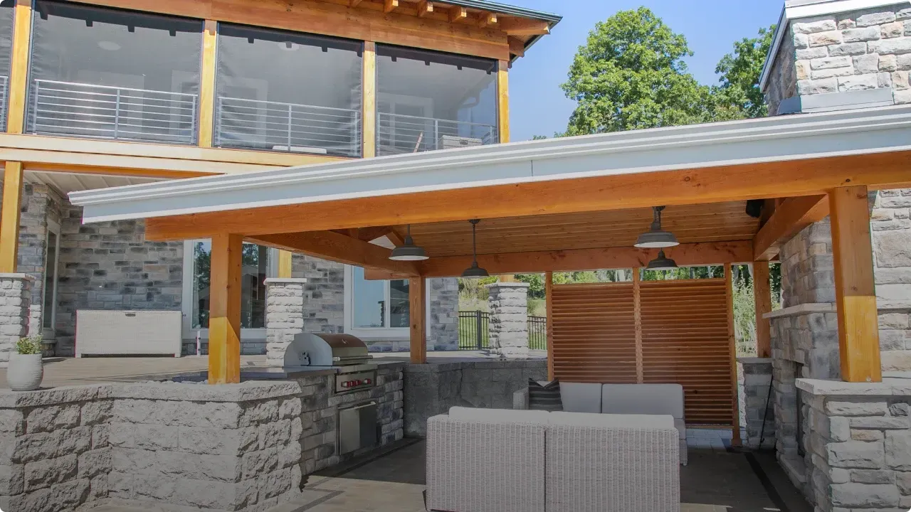 Stone-and-wood patio with a covered pergola, stone walls, and a shaded dining area outdoors