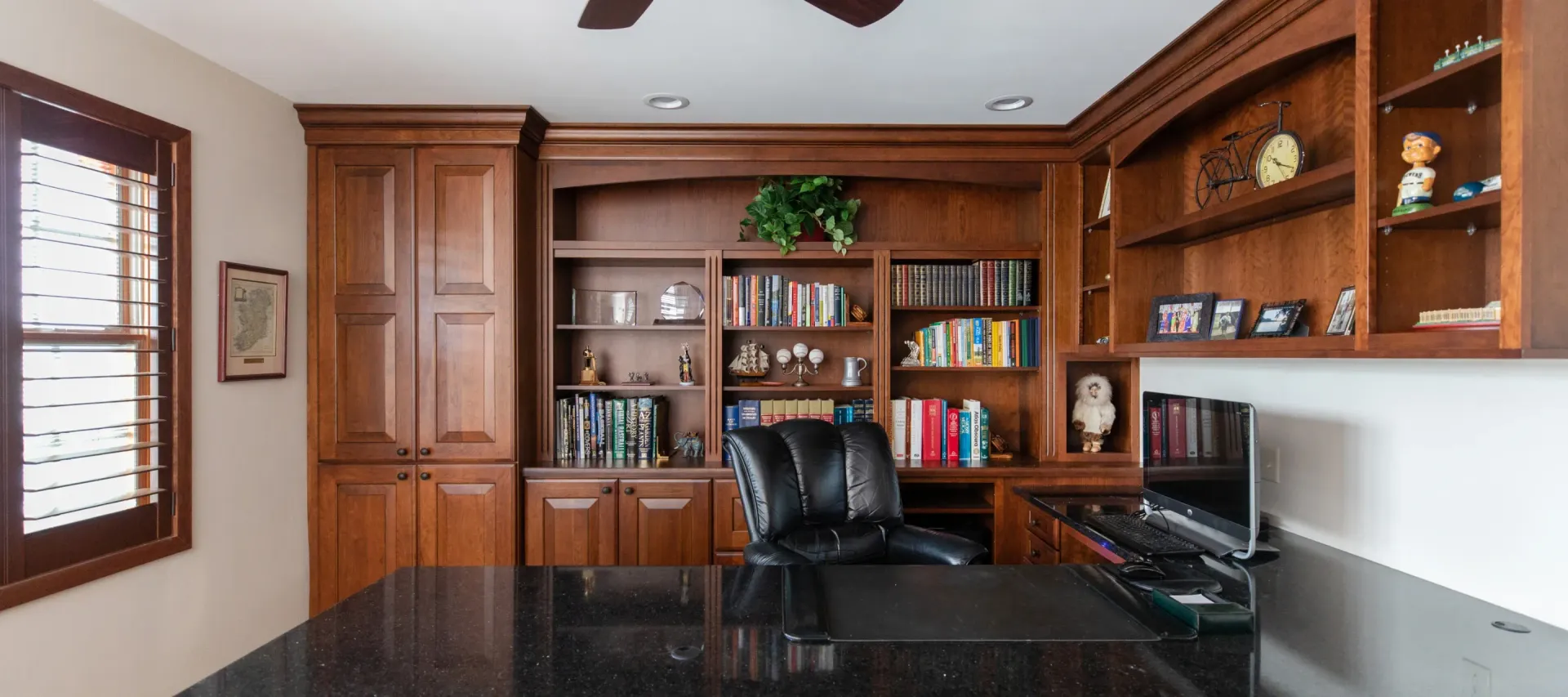 Wood-paneled home office with built-in bookshelves, desk, and leather chair