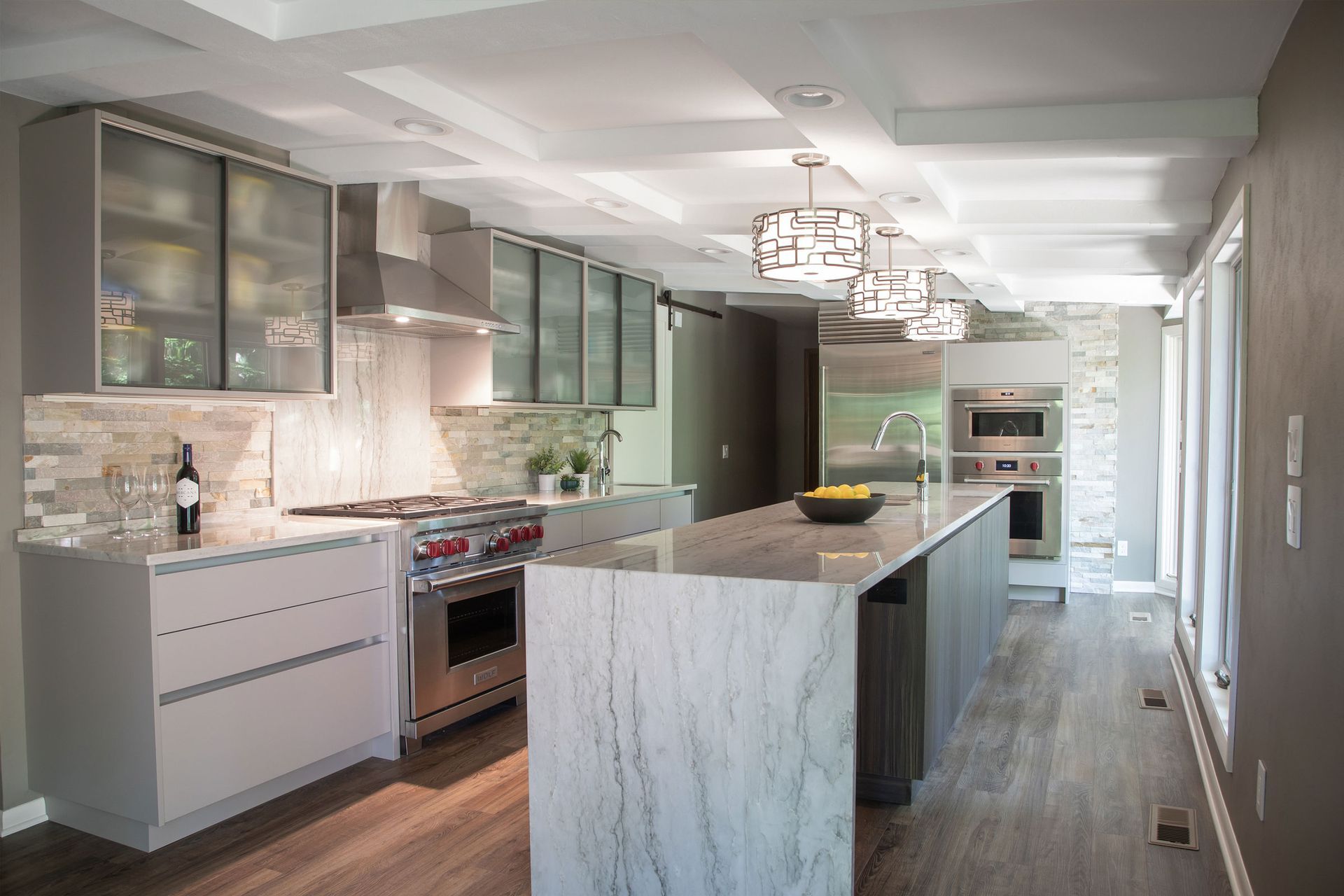 Modern white kitchen with marble island, built-in appliances, and pendant lights