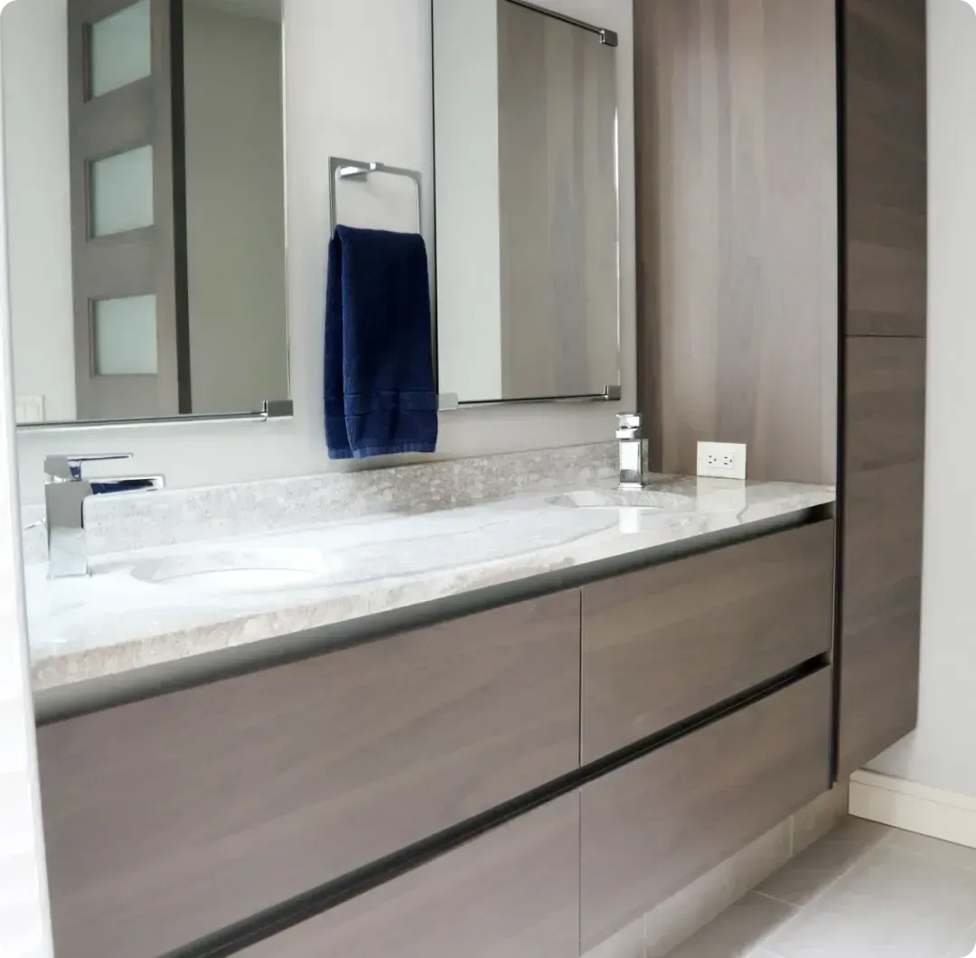 Modern bathroom vanity with marble countertop, double mirrors, and a dark blue towel hanging on the rack
