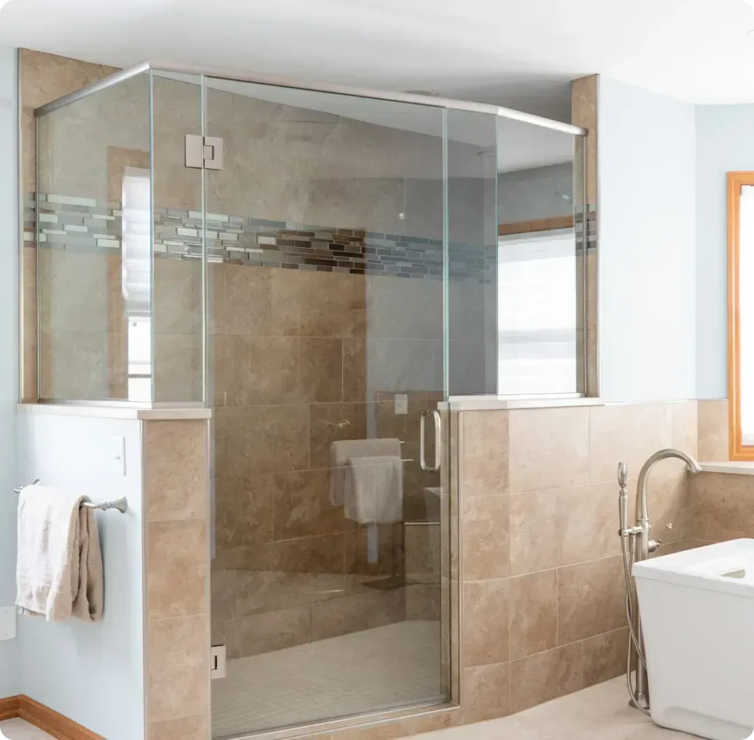 Modern bathroom with a glass-enclosed shower, beige tile, and a sink at right