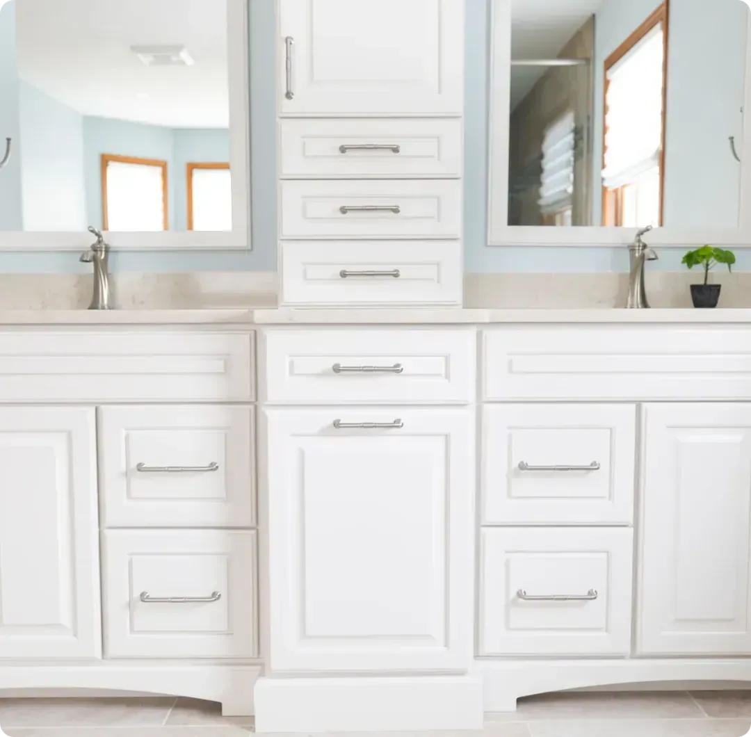 Bright white bathroom vanity with double sinks, mirrors, and central drawers in a modern, airy space