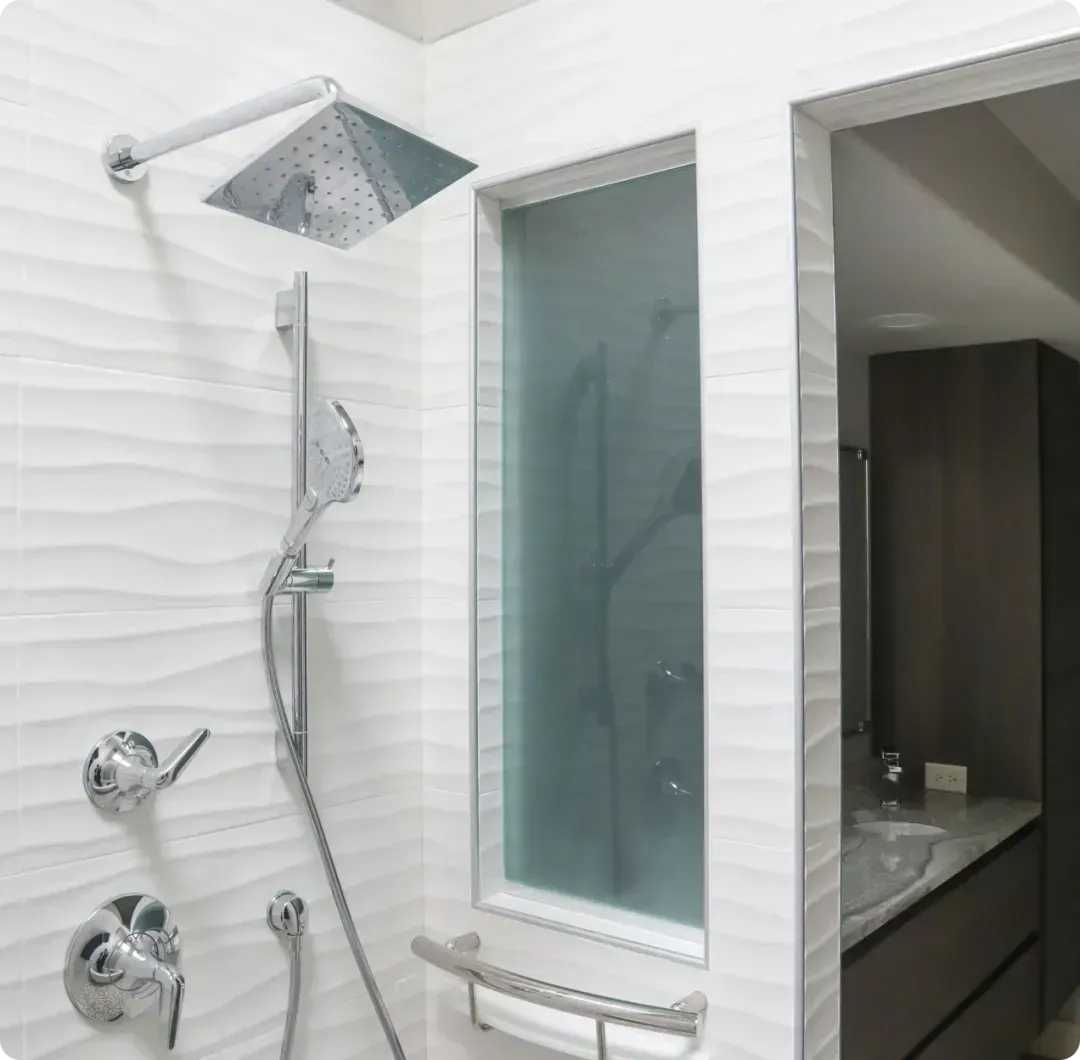 Modern bathroom shower area with chrome fixtures, frosted glass panels, and a built-in shelf.