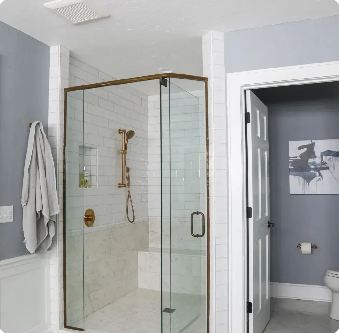 Modern bathroom with glass shower, beige tile, gray walls, and open door to a toilet room