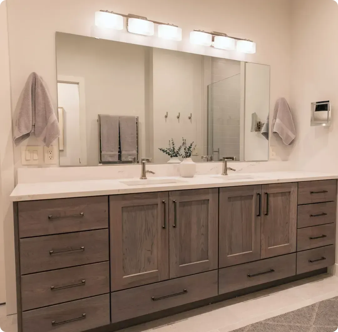 Modern double-sink bathroom vanity with wood cabinets, large mirror, and wall lights.