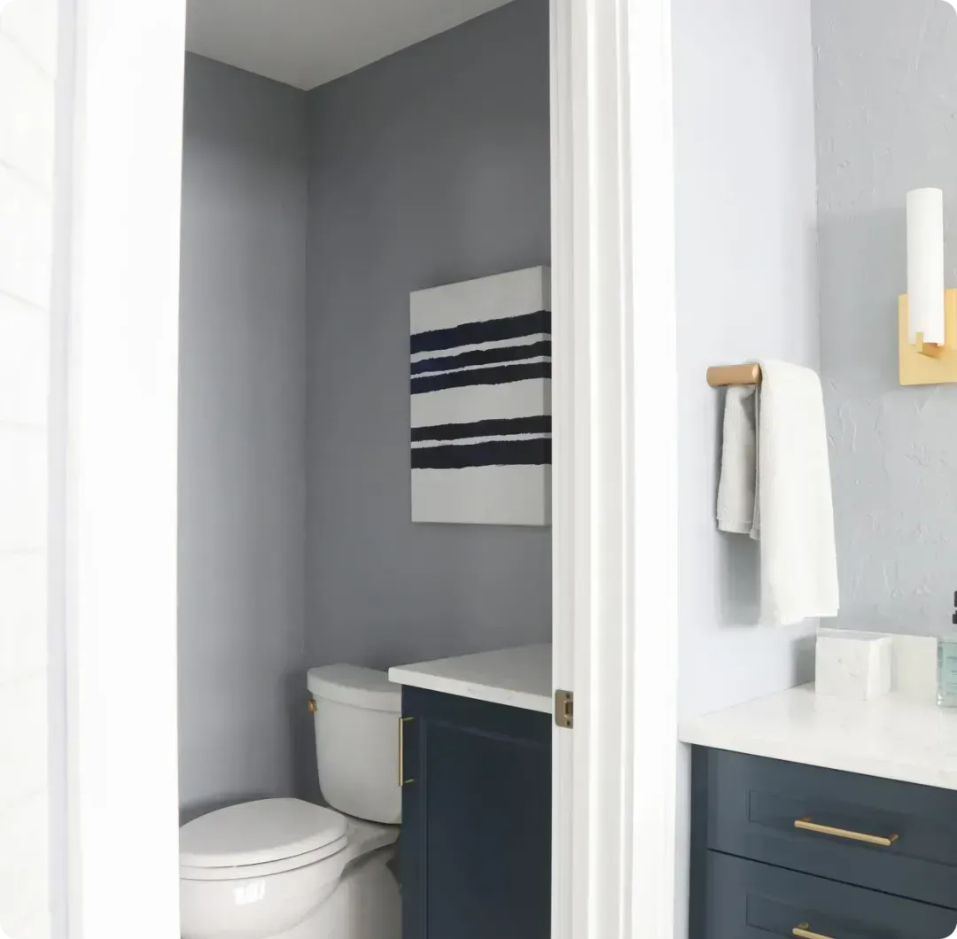 Small gray bathroom with toilet, vanity, and striped wall art.