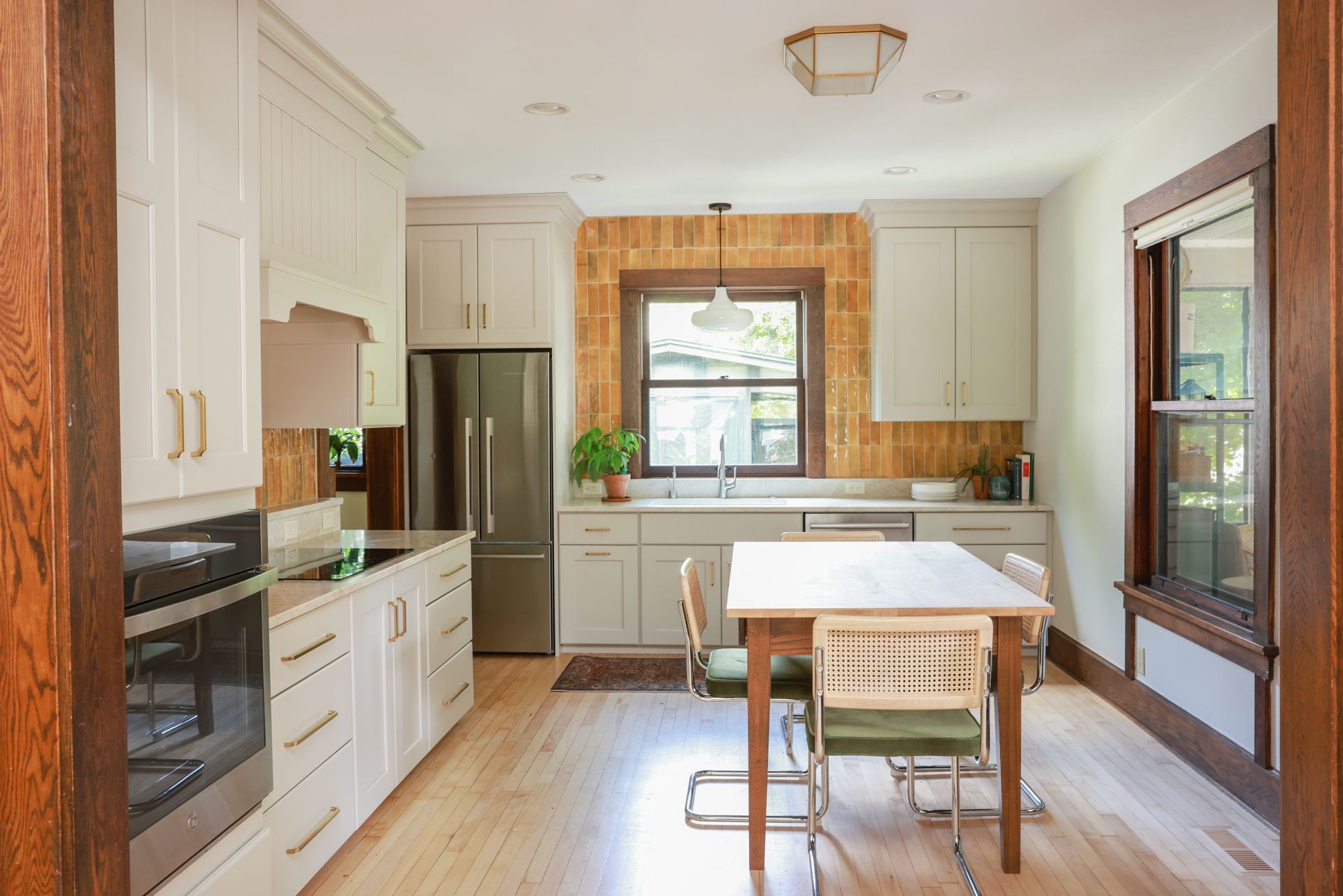 Bright modern kitchen with white cabinets, stainless fridge, wood floors, and a small island.