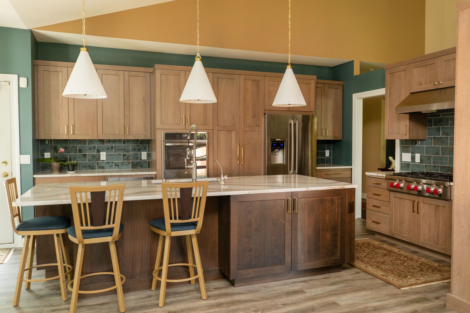 Spacious kitchen with wood cabinets, island seating, pendant lights, and stainless steel appliances.