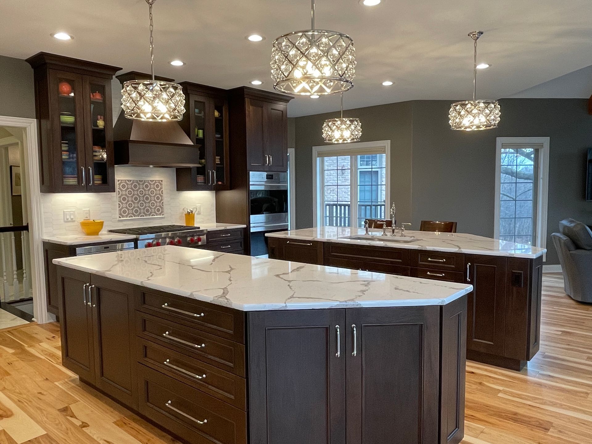Modern kitchen with dark wood cabinets, white countertops, large island, and pendant lights
