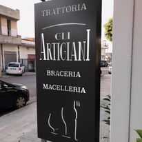 Un cartello in bianco e nero per un ristorante chiamato trattoria gli artigiani.