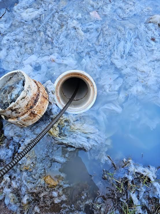 Two open pipes in icy blue water with a cable or hose entering one pipe.