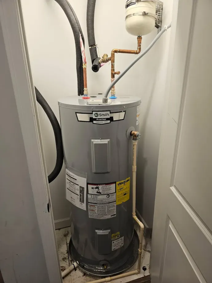 Gas water heater in a closet with pipes and venting above it.
