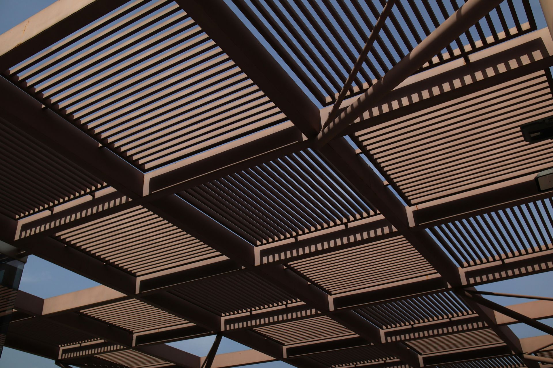 Abstract view of wooden slatted pergola panels against a blue sky