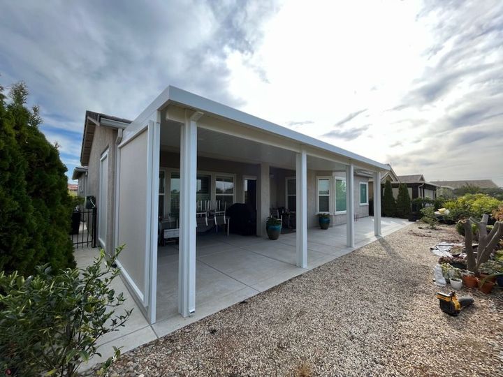 Modern house patio with white posts, gravel ground, and outdoor seating under a covered roof
