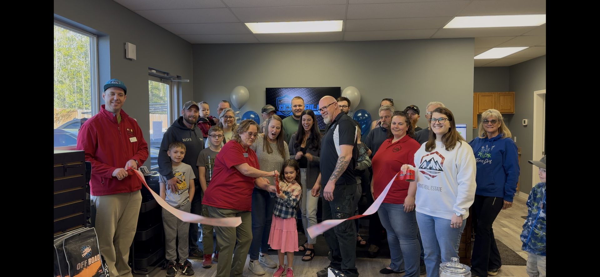 A group of people are standing in a room cutting a ribbon.