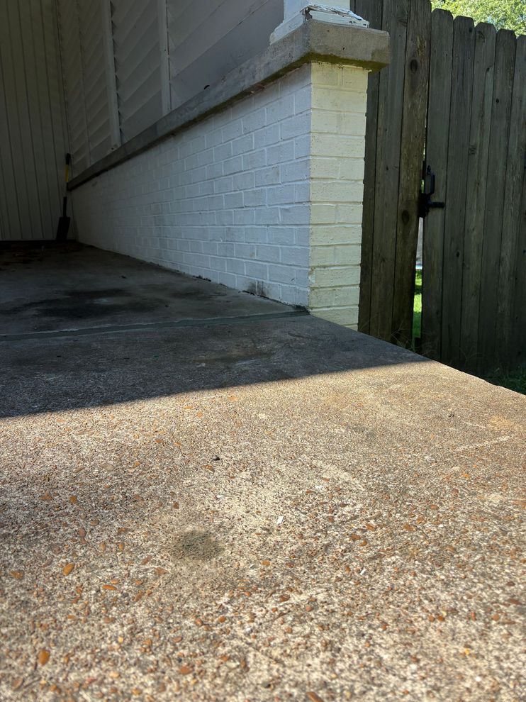 A person uses a rotary hammer drill to create a series of holes in a concrete surface with metal rods already inserted.